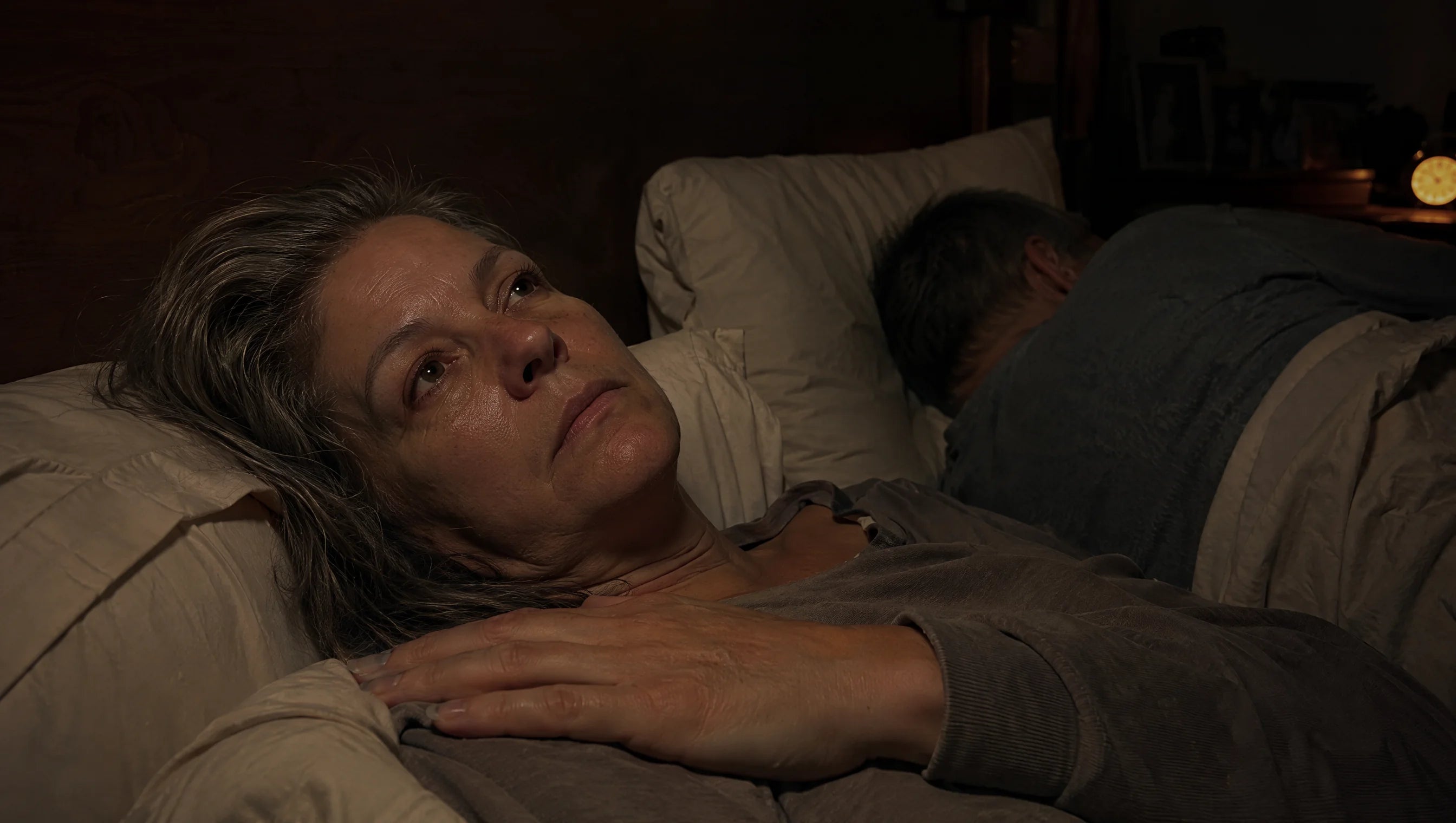 Woman awake at night with shoulder pain while her partner sleeps